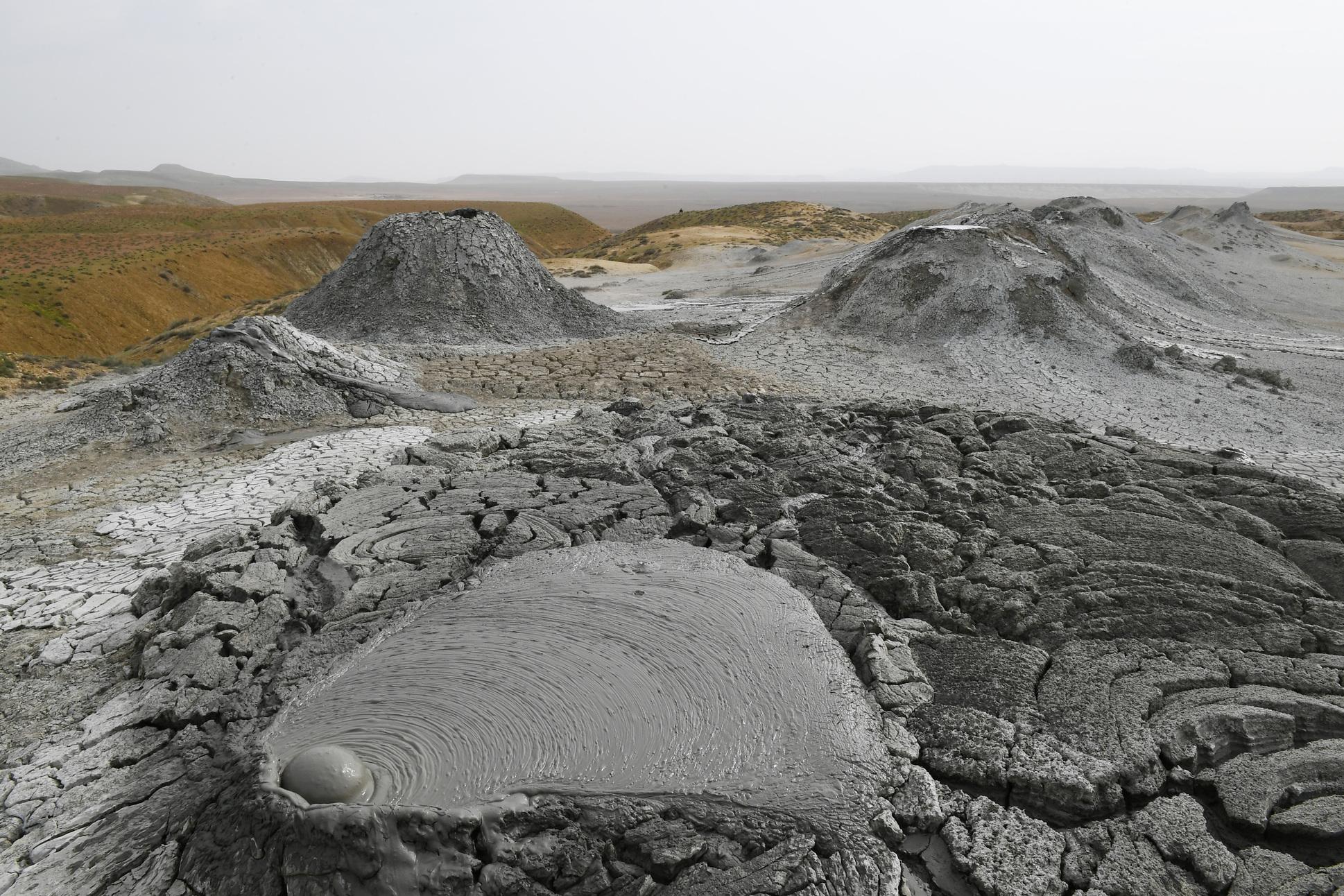 <h3>MUD VOLCANOES</h3>Mud volcanoes are a unique geological phenomenon found in several regions around the world, including Azerbaijan, where they are particularly notable. These formations are not true volcanoes in the traditional sense, as they do not erupt molten lava. Instead, mud volcanoes emit a mixture of water, gases (primarily methane), and sedimentary mud, which are pushed to the surface through vents in the earth's crust. In Azerbaijan, mud volcanoes are concentrated in the coastal areas around Baku and the Caspian Sea, creating a surreal landscape of small mounds with bubbling mud pools. The mud emitted by these volcanoes is believed to have therapeutic properties and is used in local spa treatments. Tourists often visit these sites to witness the unique natural spectacle and explore the lunar-like terrain, which is unlike any other landscape in the world.