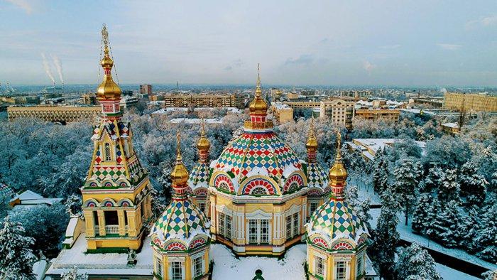 <h3>PANFILOV PARK AND ZENKOV CATHEDRAL </h3>Panfilov Park, located in the heart of Almaty, is named in honor of the Panfilov Heroes, a group of soldiers who bravely defended Moscow during World War II. The park is a tranquil oasis with tree-lined paths, flower gardens, and recreational areas popular among locals and tourists alike. At the park's center stands the Ascension Cathedral, also known as Zenkov Cathedral, renowned for its distinctive Russian Orthodox architecture. Built entirely of wood without the use of nails, it is considered one of the tallest wooden buildings in the world. Completed in 1907, the cathedral's vibrant colors and intricate details highlight its historical and cultural significance as a symbol of faith and resilience in Almaty's architectural landscape.