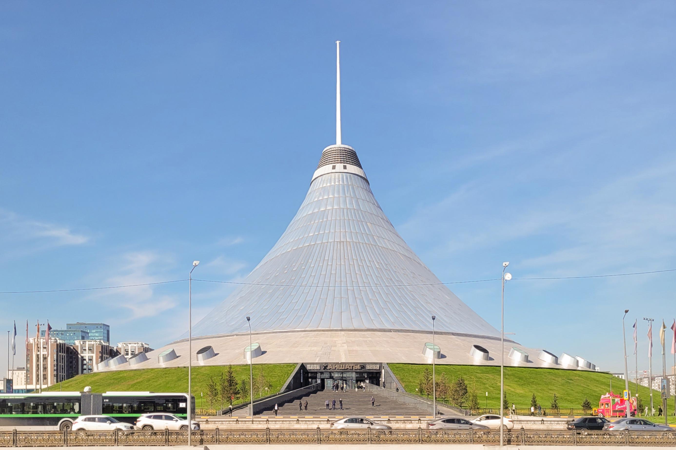 <h3>KHAN SHATYR ENTERTAINMENT CENTER</h3>The Khan Shatyr Entertainment Center in Nur-Sultan is a distinctive architectural marvel and a popular attraction in Kazakhstan's capital city. Designed by the British architect Norman Foster, this massive tent-shaped structure stands 150 meters tall and covers an area of 140,000 square meters, making it one of the largest tents in the world. It houses an indoor beach resort with sand imported from the Maldives, shopping malls, restaurants, cafes, and entertainment venues. The transparent roof allows natural light to illuminate the interior, creating a pleasant environment year-round. The Khan Shatyr not only serves as a leisure destination for locals and tourists but also symbolizes Nur-Sultan's modernity and ambition in blending functionality with innovative design.