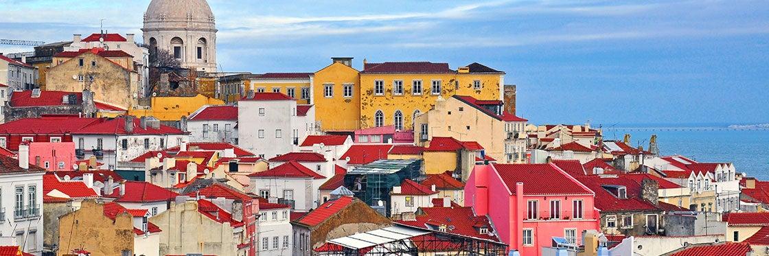 <h3>ALFAMA </h3>Alfama é o bairro mais antigo e pitoresco de Lisboa, conhecido por suas ruas estreitas e sinuosas, arquitetura histórica e cultura tradicional do Fado. Localizado em uma colina, Alfama mantém muito do seu charme medieval com vielas labirínticas, fachadas azulejadas e praças aconchegantes. As principais atrações incluem o Castelo de São Jorge, uma fortaleza mourisca que oferece vistas panorâmicas da cidade, e a Catedral de Lisboa (Sé de Lisboa), uma igreja românica que data do século XII. Alfama também é famosa por suas casas de Fado, locais íntimos onde a melancólica música folclórica portuguesa é apresentada todas as noites. Os visitantes podem explorar as lojas locais de Alfama, tabernas acolhedoras que servem pratos tradicionais como sardinhas assadas, e miradouros que oferecem vistas deslumbrantes sobre o rio Tejo. Este bairro encanta os visitantes com sua atmosfera autêntica, importância histórica e vibrante cultura, tornando-o uma área imperdível em Lisboa.