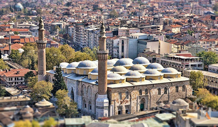<h3>ULU CAMİİ</h3>Ulu Cami, Bursa'nın en büyük camisidir ve erken dönem Osmanlı mimarisini temsil eden önemli bir yapıdır. Bu cami Osmanlı Padişahı I. Bayezid tarafından 1396-1400 yılları arasında Mimar Ali Neccar tarafından yaptırılmıştır. Toplam 12 sütunla desteklenen ve iki minareye sahip olan Ulu Cami, mimari zarafeti ve estetiğiyle dikkat çekiyor. Özellikle, Ulu Cami'nin iç kısmındaki çok sayıda küçük kubbe, erken dönem Osmanlı camilerinin benzersiz bir özelliğidir. Bu cami, Konstantinopolis'in fethinden sonra inşa edilen diğer camilerden farklıdır. Genel olarak, bu dönemin camilerinde çıplak gözle görülemeyen bir atmosfer yaratan birçok küçük kubbe vardı. Ancak Ulu Cami, 1453'ten sonraki camilere özgü merkezi ve büyük bir kubbeye sahiptir. Bu tasarım Ayasofya'nın mimarisinden esinlenmiştir. Ulu Cami'nin merkezi kubbeleri, Allah'ın ilahi gücünü vurgulayarak ibadet edenlere görkemli ve güçlü bir atmosfer sunmayı amaçlamaktadır. Bu mimari detaylar, Osmanlı döneminin sanatsal ve dini ifadesinde önemli bir rol oynamakta ve camiyi eşsiz kılmaktadır.