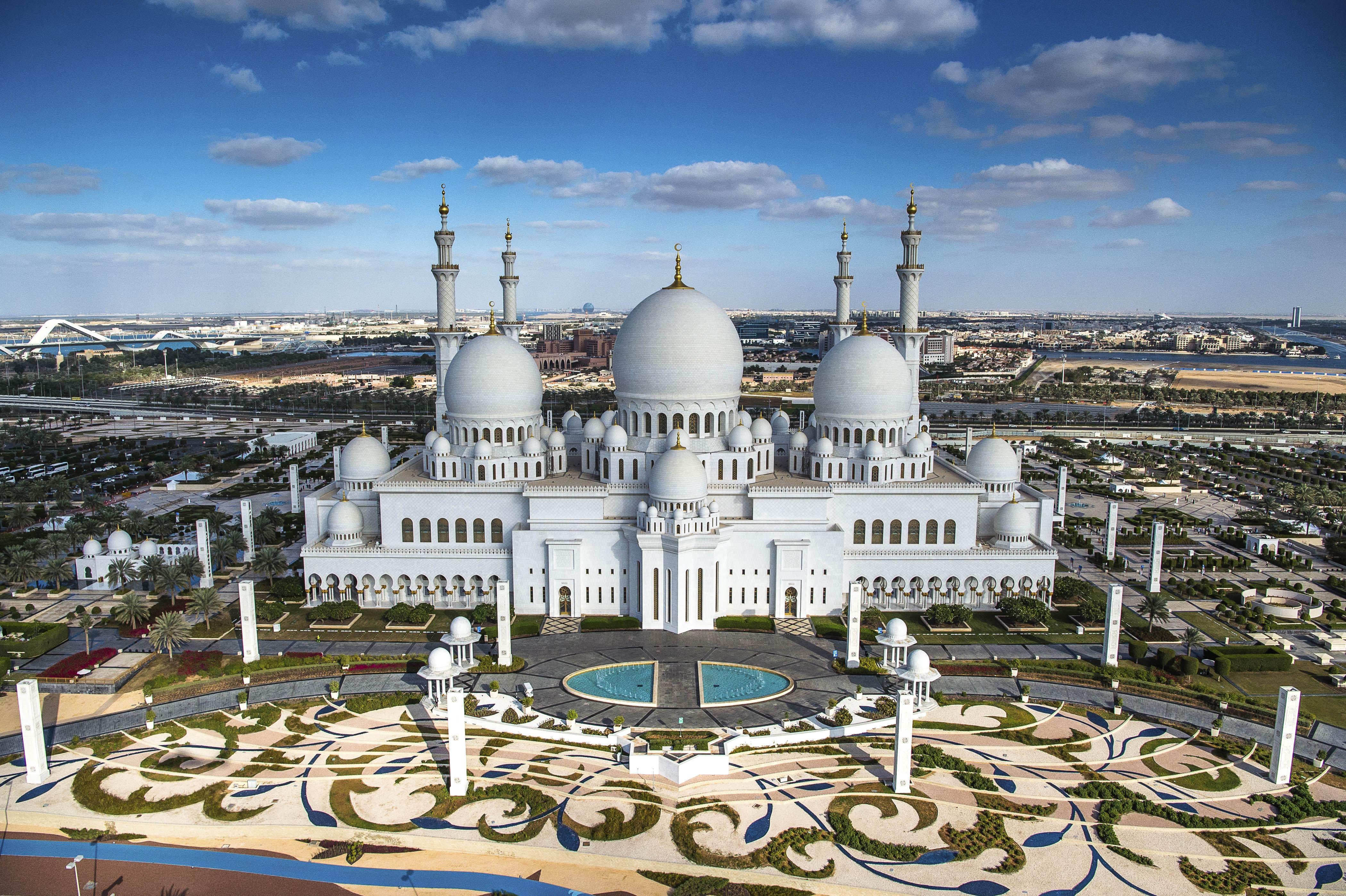 <h3>Sheikh Zayed Grand Mosque</h3>The Sheikh Zayed Grand Mosque is a stunning symbol of Islamic architecture and one of the most prominent landmarks in Abu Dhabi. Named after the founder of the United Arab Emirates, Sheikh Zayed bin Sultan Al Nahyan, it is renowned for its immense size, intricate design, and breathtaking beauty. Completed in 2007, the mosque features 82 domes, over 1,000 columns adorned with semi-precious stones, and the world’s largest handwoven carpet. Its exterior gleams with pristine white marble, while the interior boasts intricate floral designs, calligraphic inscriptions, and ornate chandeliers. Open to visitors from all backgrounds, the mosque provides a serene environment for prayer and reflection, attracting millions of visitors each year who come to admire its architectural grandeur and learn about Islamic culture and heritage.